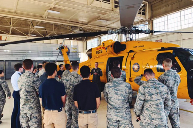 Air Force ROTC students standing in front of a helicopter listening to instructer