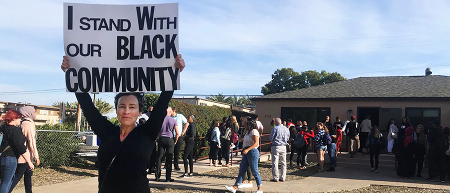 Dania Brett, University Senate Administrative Analyst, holds a sign that says "I stand with our black community" outside the Black Resource Center on the afternoon of April 15, 2019.