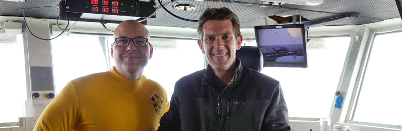 Temple Northup sits in the captain's chair next to Captain Joshua "Spoiler" Wenker on the bridge of the USS Nimitz.