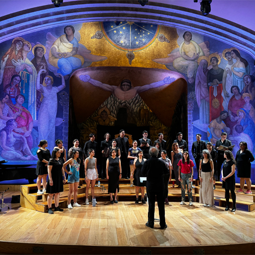 The choir performing in Anfiteatro Simón Bolívar under a mural by Diego Rivera (photo courtesy of Arian Khaefi)