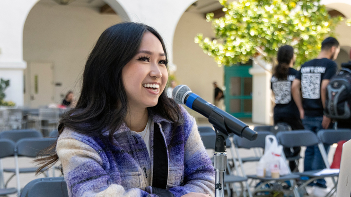 Journalism student Hannah Ly behind a microphone.