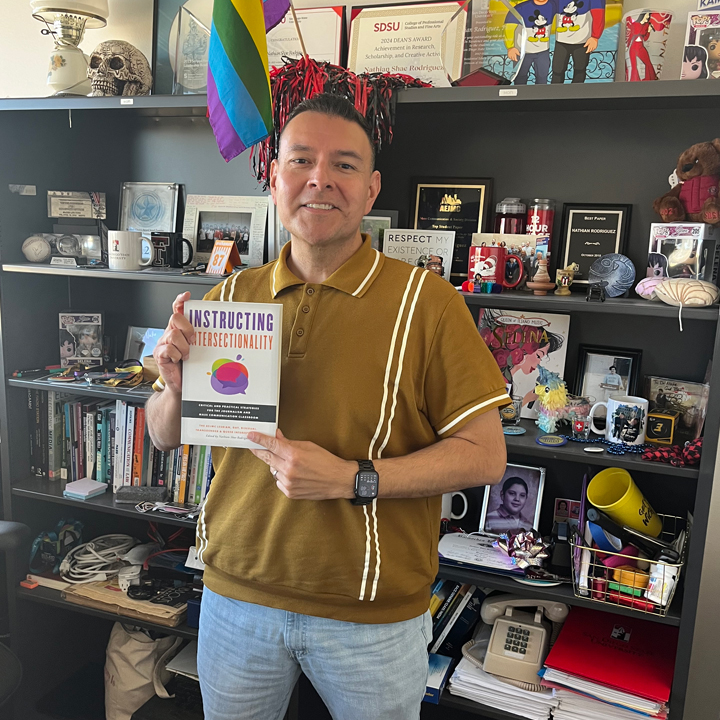 Dr. Rodriguez holds his new book in his office. Photo credit: Reagan Verschelde.