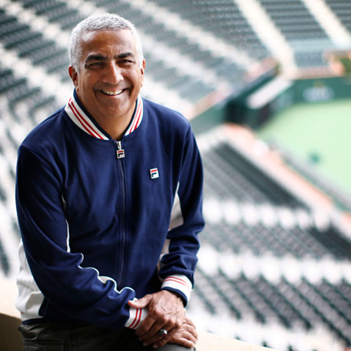 J. Fred Sadu poses in front of tennis court