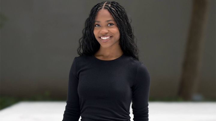 Portrait of art and design alumna Maya Davis smiling against a neutral background.